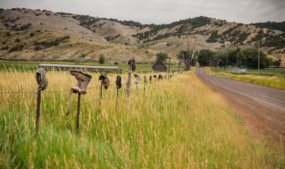 field in gypsum with a barb wire fence that has boots on the fence posts