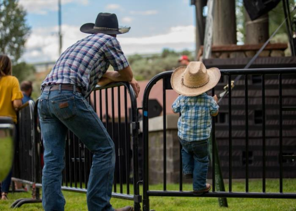 an adult and child leaning on the fence at gypsum daze